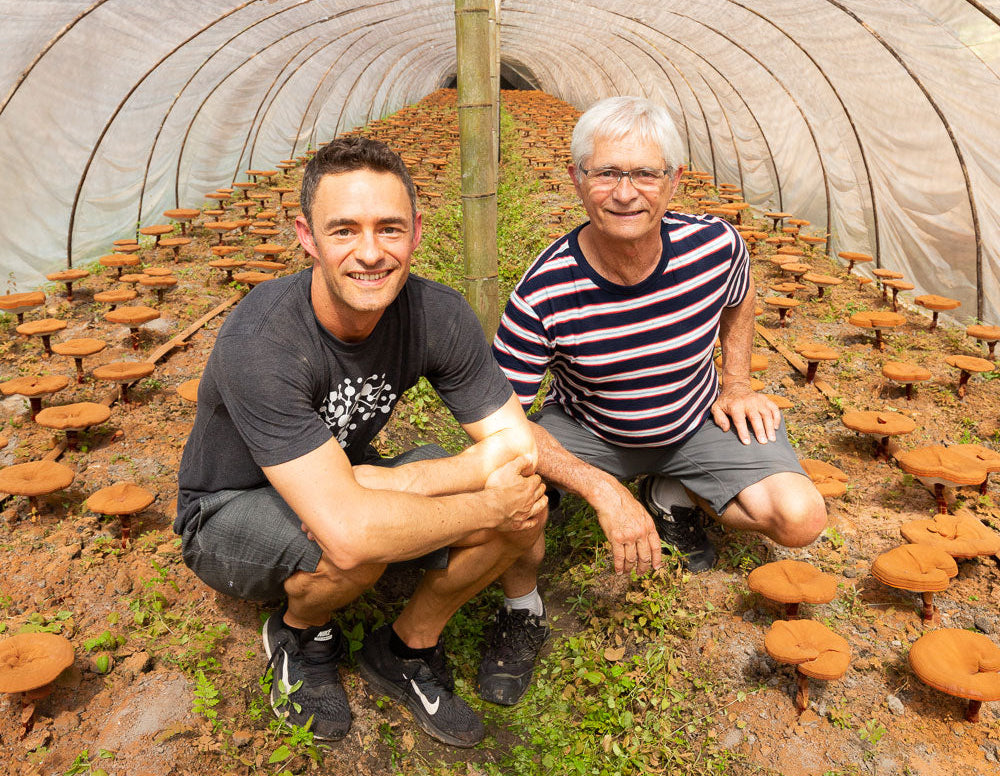 Two people inside a mushroom growing facility with rows of mushroom cultivation.